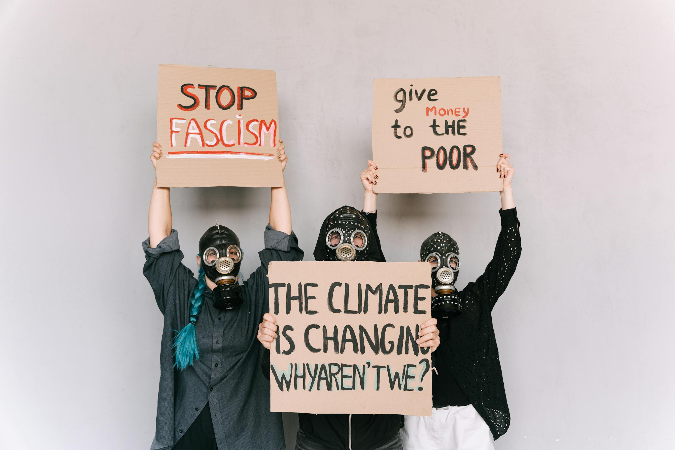 Three People With Gas Masks Holding Posters